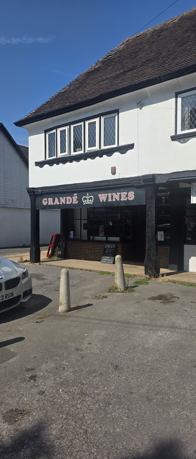 Grandé Wines, a shopfront with a black fascia and pink lettering in a white mock-Tudor building