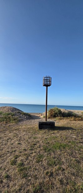 The beacon on the Greensward, a tall post topped with an iron fire basket, against the sea