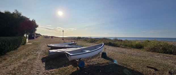 Small boats under covers on the Greensward in low evening sun, with the beacon beyond