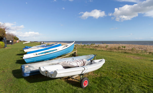 Small boats pulled up on the grass of the Greensward beside the shingle
