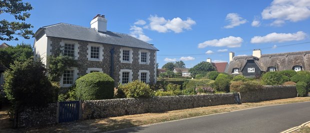 Flint Cottage on Sea Lane, a flint-faced house with painted brick quoins behind a low flint wall