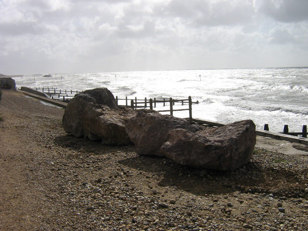 Rock armour boulders stacked on the beach awaiting placement